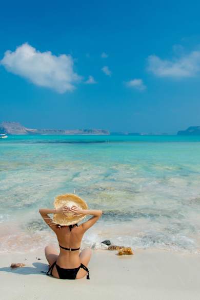 Mädchen im schwarzen Bikini und mit Hut am Strand von Balos © GettyImages